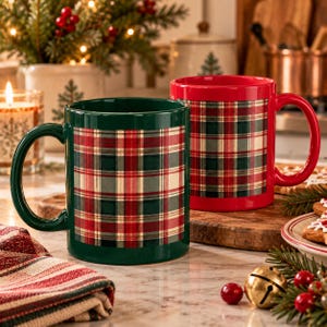 Pode incluir: Duas canecas de cerâmica, uma verde-escura e outra vermelha brilhante, ambas com uma faixa central com um padrão clássico de xadrez vermelho, verde e creme. Cada caneca tem uma alça resistente e um acabamento liso e brilhante.