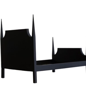 May include: A black wooden bed frame with a unique design. The headboard and footboard feature a distinctive shape with pointed finials. The bed frame is made of solid wood and has a minimalist aesthetic.