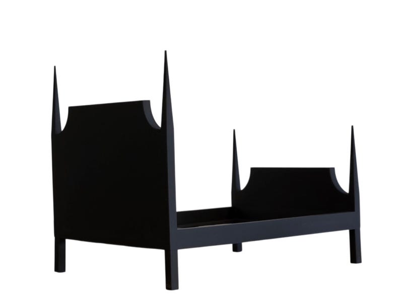 May include: A black wooden bed frame with a unique design. The headboard and footboard feature a distinctive shape with pointed finials. The bed frame is made of solid wood and has a minimalist aesthetic.