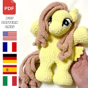 May include: A crochet plush toy of a yellow pony with a light brown mane and tail. The text PDF PATTERN ONLY is displayed alongside icons of a PDF file and the flags of the United States, France, Germany, Spain, and Italy, indicating language options.