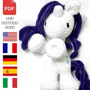 May include: A white crocheted unicorn toy with purple hair and tail. The unicorn has a horn and blue details. The image includes a PDF icon and the text "PDF PATTERN ONLY".