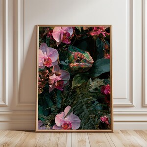 Peut inclure: Une impression d'art mural verticale encadrée représentant une illustration détaillée d'un caméléon vert et orange niché parmi des orchidées roses vibrantes et un feuillage vert foncé. L'œuvre est dans un cadre en bois clair.