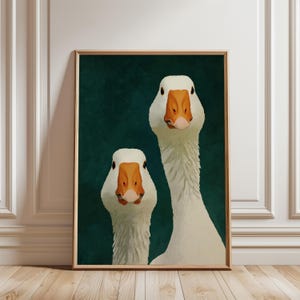 May include: A framed wall art print featuring two white geese with orange beaks positioned against a dark forest green background. The geese are shown from the chest up, facing forward with their long necks visible in a vertical composition.