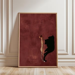 May include: A framed vertical wall art print featuring a spotted cheetah climbing upwards against a deep burgundy textured background. To the right of the cheetah, a solid black silhouette of a large feline is cast, mirroring the climbing motion.