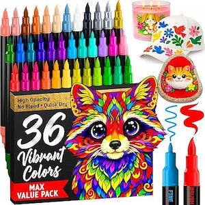 May include: A set of 36 vibrant colour markers in a black box featuring a colourful raccoon illustration. The box displays the text 36 Vibrant Colours, High Opacity, No Bleed, Quick Dry, and Max Value Pack. Includes a white cap with floral patterns, a painted rock with a cat face, and a pink candle.