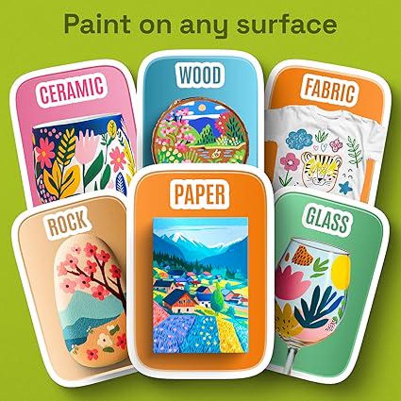 May include: A graphic display titled Paint on any surface featuring six rectangular cards labelled Ceramic, Wood, Fabric, Rock, Paper, and Glass. Each card shows a painted example on that specific material, including a mug, wood slice, t-shirt, stone, landscape painting, and wine glass.