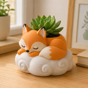 May include: A planter shaped like a sleeping orange fox with a white-tipped tail, resting on a white cloud-shaped base. The fox has closed eyes and a black nose. A green succulent plant is growing out of the top of the fox's back.