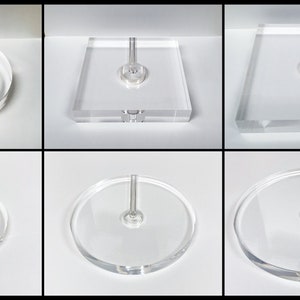 May include: Eight clear acrylic display stands with a central post. The stands are in various shapes, including round and square.