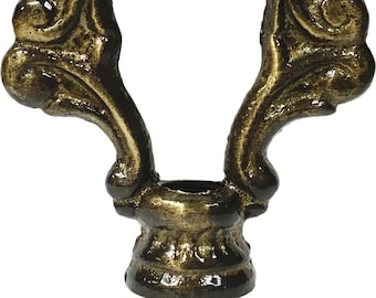 May include: Ornate bronze-colored lamp finial with a decorative, openwork design. The finial features a scrolling, symmetrical pattern with a central opening and a detailed base. The finish has a slightly aged appearance, adding to its vintage appeal.