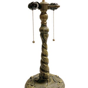 May include: A gold-toned table lamp base with a twisted design and dragonfly accents. The base has two pull chains for controlling the light.