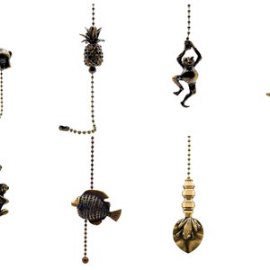 May include: Assortment of decorative fan pull chains with various designs, including a pineapple, an elephant, a monkey, a fish, and a frog. The chains are made of metal and have a gold finish.