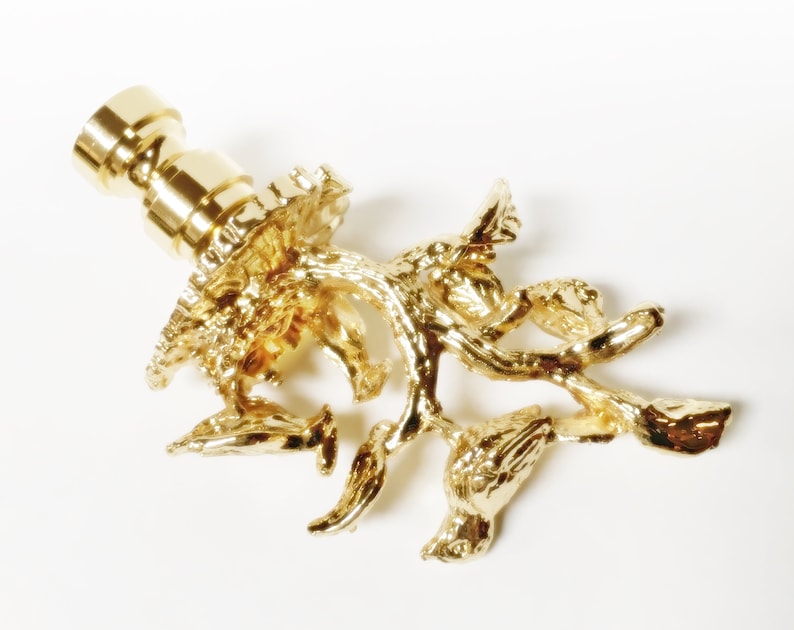 May include: Gold-toned metal lamp finial with a detailed design of a tree branch with birds perched on it.