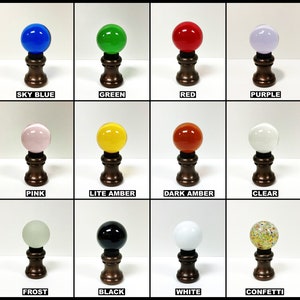 May include: Twelve different colored glass finials for lampshades. The finials are all round and have a bronze base. The colors are sky blue, green, red, purple, pink, light amber, dark amber, clear, frost, black, white, and confetti.