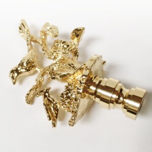 May include: Gold metal finial with a bird and nest design. The finial is a decorative element used on the top of curtains, drapes, or other home decor items.
