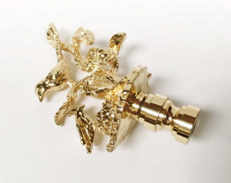 May include: Gold metal finial with a bird and nest design. The finial is a decorative element used on the top of curtains, drapes, or other home decor items.