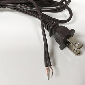 May include: A brown electrical cord with a two-prong plug and exposed wires.