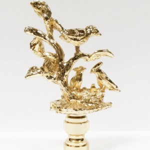 May include: Gold metal lamp finial with a detailed design of birds in a nest on a tree branch.