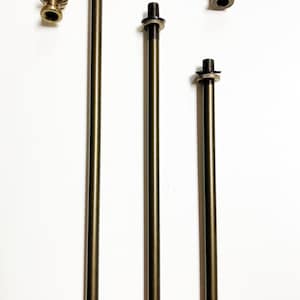 May include: Three different sized metal rods with threaded ends and decorative finials. The rods are a dark bronze color and the finials are a lighter gold color.