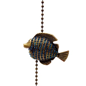 May include: A gold chain with a blue and gold jeweled fish pendant. The chain is attached to a small gold ball at the bottom.