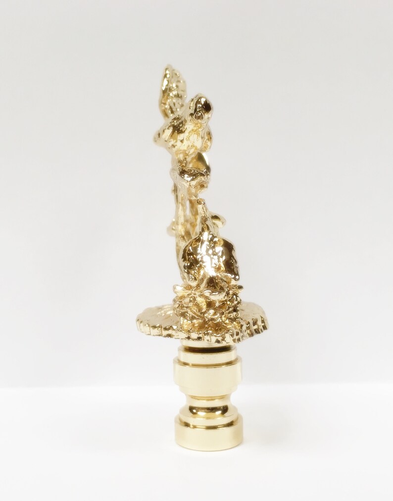 May include: Gold-toned metal lamp finial with a detailed design of birds perched on a branch. The finial has a round base.