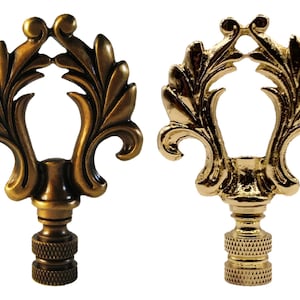 May include: Two ornate lamp finials with a gold finish. The finial on the left has a more antique brass finish, while the finial on the right has a polished gold finish. Both finials feature a decorative leaf design.