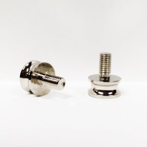 May include: Two silver metal furniture feet with a threaded screw and a round base.