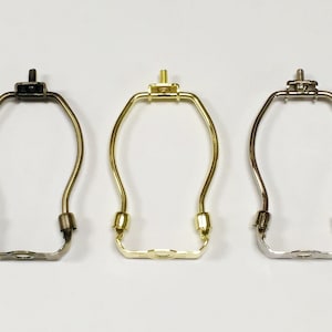 May include: Three lamp harp sockets in different finishes: black, gold, and silver. Each harp socket is made of metal and has a curved shape.