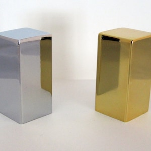 May include: Two decorative square boxes, one silver and one gold, with a shiny, reflective finish.