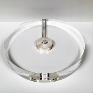 Może przedstawiać: Transparentny gramofon akrylowy ze srebrnym metalowym środkiem. Gramofon jest zaprojektowany do trzymania płyty.