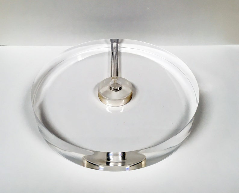 Może przedstawiać: Transparentny gramofon akrylowy ze srebrnym metalowym środkiem. Gramofon jest zaprojektowany do trzymania płyty.