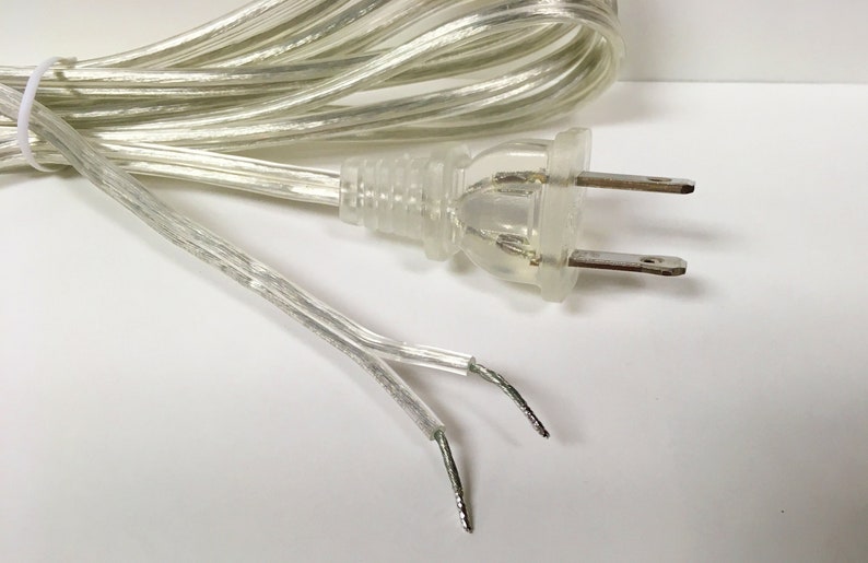 May include: A clear, transparent electrical cord with a two-prong plug. The cord is coiled and the ends are visible.