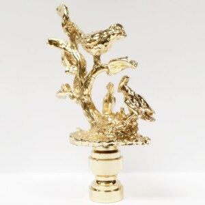 May include: Gold lamp finial with a bird perched on a branch with two baby birds in a nest.