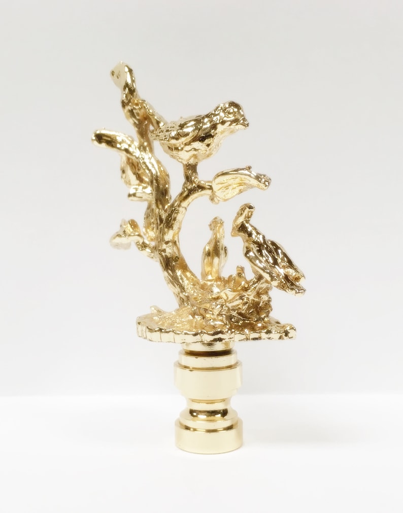 May include: Gold lamp finial with a bird perched on a branch with two baby birds in a nest.