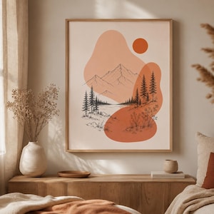 以下が含まれることがあります： オレンジと黒の色合いの太陽と抽象的な形が描かれた山岳風景の額入りアートプリント。 アートワークは木製のフレームに入っており、明るい色の壁に飾られています。
