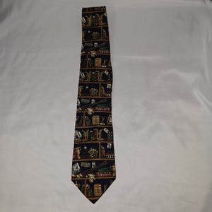 May include: A dark navy blue necktie featuring a repeating grid pattern. Each rectangular section contains illustrations of billiard equipment, including pool cues, racks of billiard balls, trophies, and playing cards, set against a dark background.