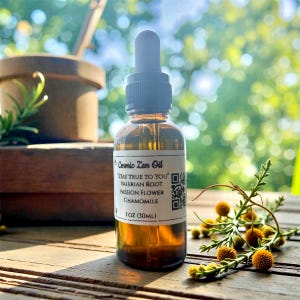 May include: A brown glass bottle of Cosmic Zen Oil with a dropper, labelled with ingredients including Valerian Root and Chamomile. The bottle contains 30ml of oil. The background is a wooden surface with greenery.
