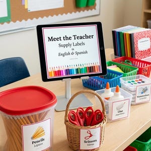 Op de afbeelding: Een tablet op een standaard toont Meet the Teacher Supply Labels in English & Spanish met een potloodafbeelding. Ernaast staan doorzichtige bakjes met potloden, lijm en waterverf, plus een gevlochten mandje met rode scharen en labels.