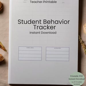 May include: A white Student Behavior Tracker printable with the text "Student Behavior Tracker Instant Download." The notebook has sections for overall notes and action steps. Dried flowers and foliage are arranged around the notebook.