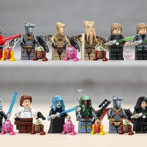 May include: A collection of sixteen LEGO Star Wars minifigures and small droid figures arranged in two rows. The figures include various characters with lightsabers, blasters, and helmets, alongside several colorful astromech and spherical droids.