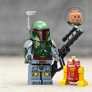 May include: A plastic minifigure featuring a green helmet with a rangefinder, green armor, and a brown utility belt. The figure holds a black blaster rifle. A separate head piece with a printed face is shown above, and a small red and yellow droid stands nearby.