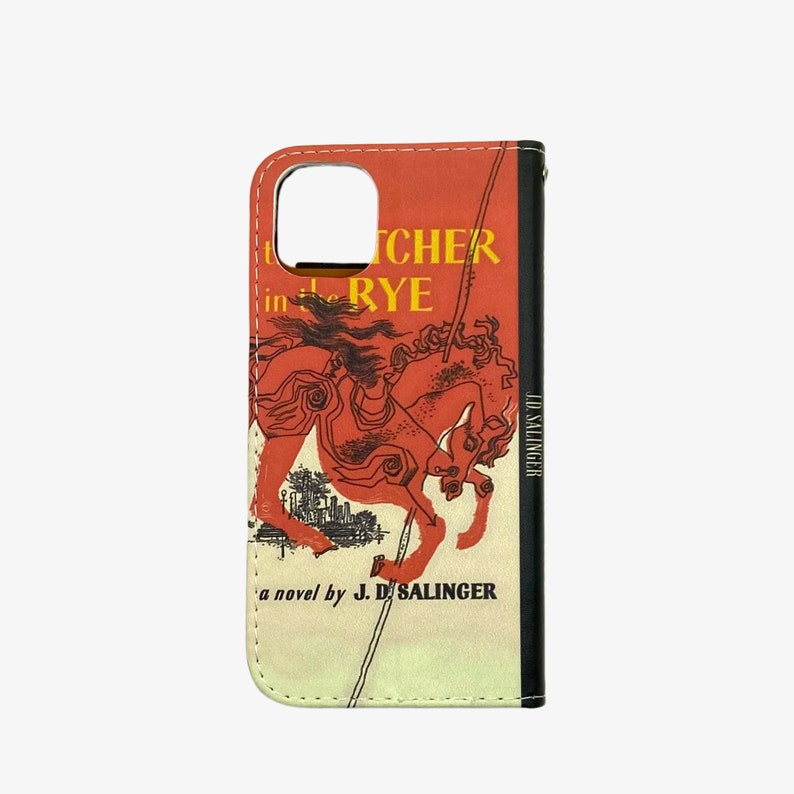 Pu&ograve; includere: Una custodia per telefono rossa e nera con un design di copertina di libro vintage. La copertina presenta un cavallo rosso e il titolo "Il giovane Holden" di J.D. Salinger.