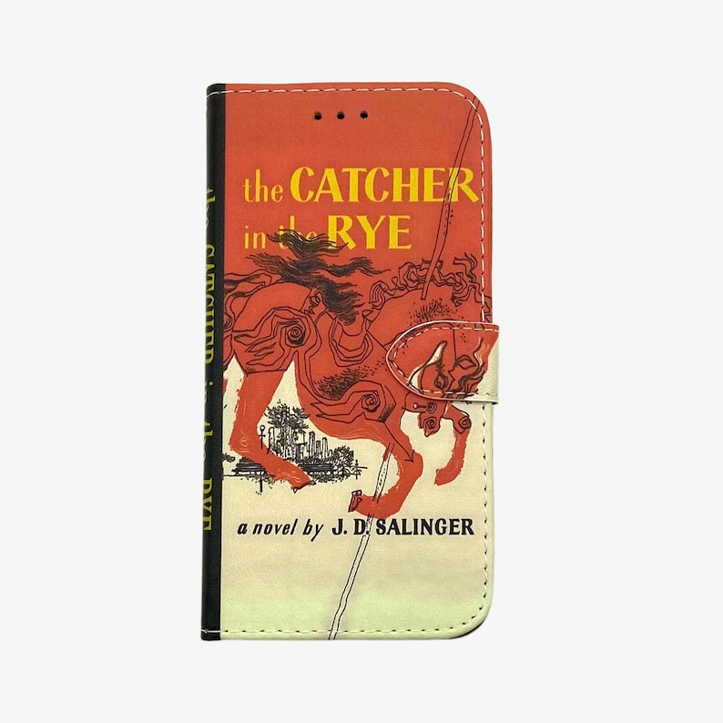 Pu&ograve; includere: Una custodia per telefono rossa e bianca con un design di copertina di libro vintage. La copertina presenta un cavallo rosso e il testo "the CATCHER in the RYE a novel by J.D. SALINGER".