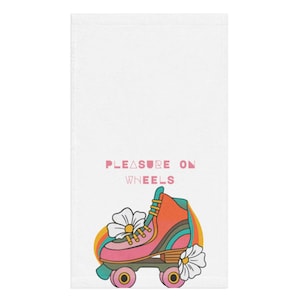 Puede incluir: Toalla de mano blanca con un diseño de patines retro, un arco iris y detalles de margaritas. El texto "PLEASURE ON WHEELS" está impreso encima del patín. El patín es rosa, naranja y turquesa.