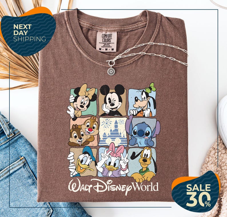 A brown t-shirt with a graphic of Disney characters, including Minnie Mouse, Goofy, Donald Duck, and Lilo, arranged in a square pattern. The t-shirt is displayed on a white background, and there are jeans and a necklace visible in the image.