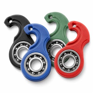 Op de afbeelding: Een verzameling van vier handzame fidget-tools in zwart, blauw, groen en rood. Elk hulpmiddel heeft een cirkelvormig frame met een centraal metalen kogellager en een gebogen haakvormig handvat met een klein gaatje aan de bovenkant.