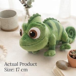 May include: A plush green chameleon toy with large brown eyes, a textured surface, and a curled tail. The stuffed animal features dark green stripes along its back and sides. The text on the image indicates an actual product size of 17 cm.