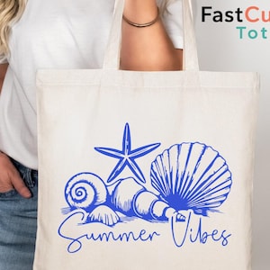May include: A cream-colored tote bag featuring a blue starfish, seashells, and the words "Summer Vibes." The bag has a simple design and is held by a person. The logo "FastCustom Totes" is in the upper right corner.