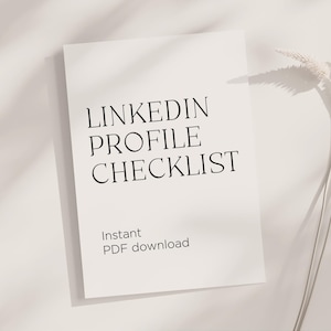May include: A white sheet of paper with the text "LINKEDIN PROFILE CHECKLIST" in black, with "Instant PDF download" below. The paper is angled, with shadows and a sprig of dried flowers in the background.
