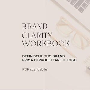 May include: A digital document titled BRAND CLARITY WORKBOOK with the subtitle DEFINISCI IL TUO BRAND PRIMA DI PROGETTARE IL LOGO and PDF scaricabile, accompanied by eyeglasses, a pen, and a spiral notebook on a light-colored surface.