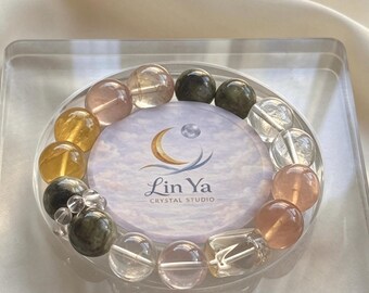 Op de afbeelding: Een kralenarmband met ronde, gepolijste edelstenen in tinten van helder, doorschijnend roze, goudgeel en donker gevlekt groen. De armband omsluit een ronde kaart met een wolkenpatroon en de tekst Lin Ya Crystal Studio.